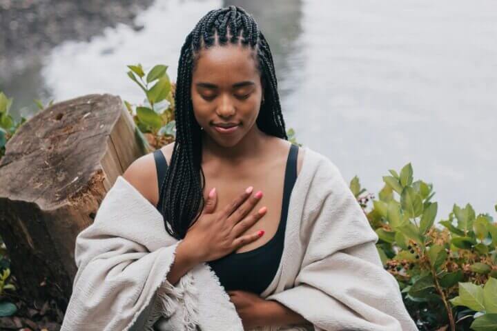 woman meditating  in black tank top and white blanket wrap around her arms